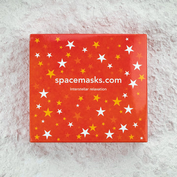 Red box with star patterns and 'spacemasks.com' text on a textured surface