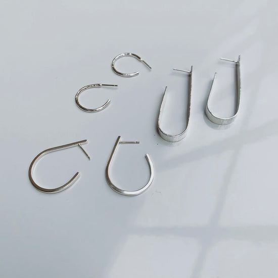 Set of silver hoop earrings on a light gray background