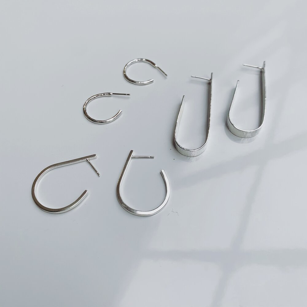 Set of silver hoop earrings on a light gray background