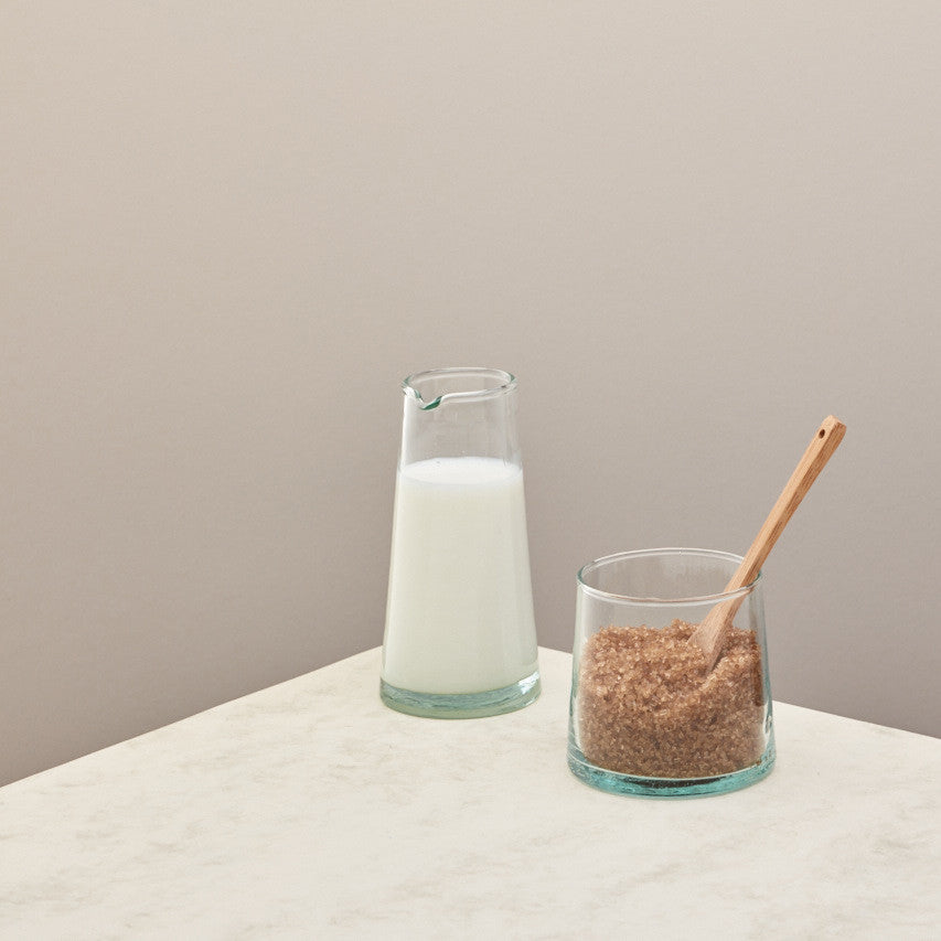 A jug of milk and a small jug of sugar on a taupe background 