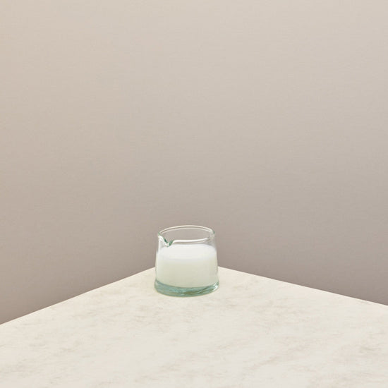 A low jug filled with milk on a taupe background 