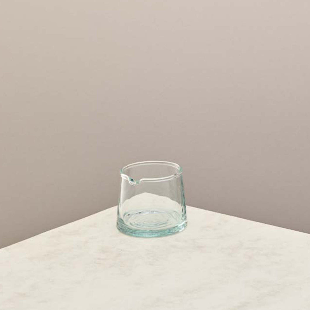 A small glass jug with a taupe background 