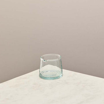 A small glass jug with a taupe background 