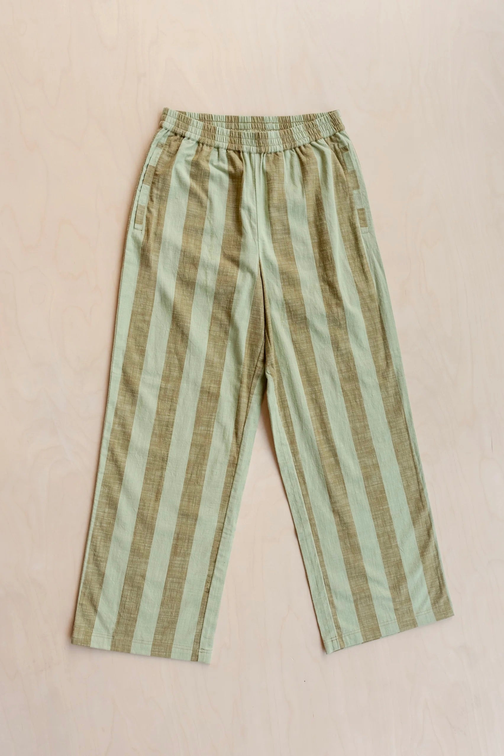 Striped trousers with green and brown pattern on a beige background