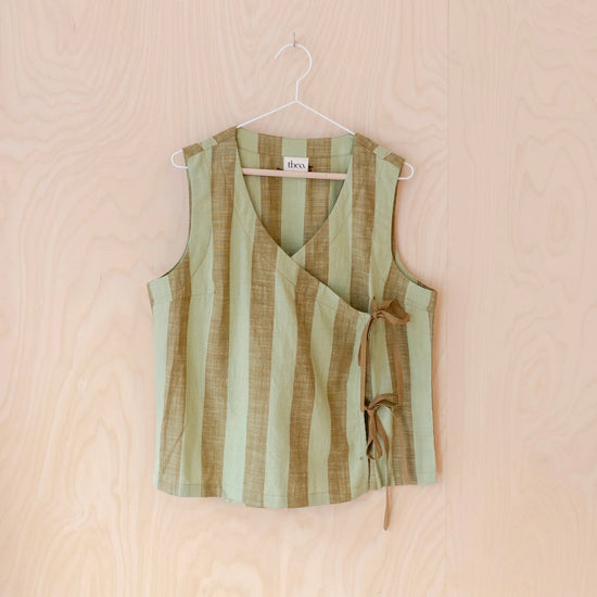 Green and brown striped sleeveless tie top on a hanger against a beige background