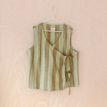 Green and brown striped sleeveless tie top on a hanger against a beige background