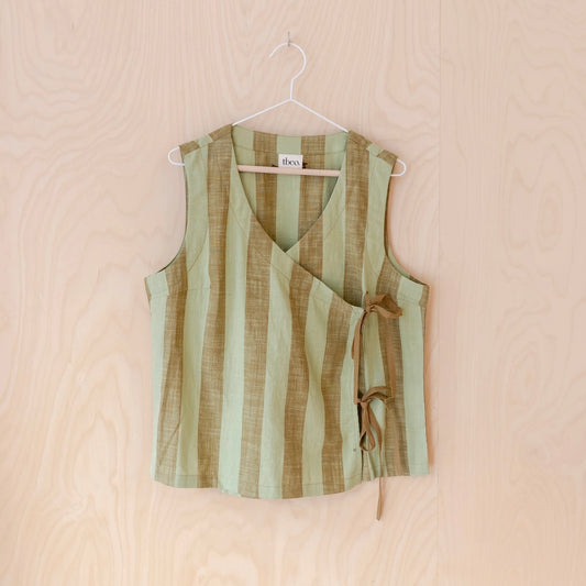 Green and brown striped sleeveless tie top on a hanger against a beige background