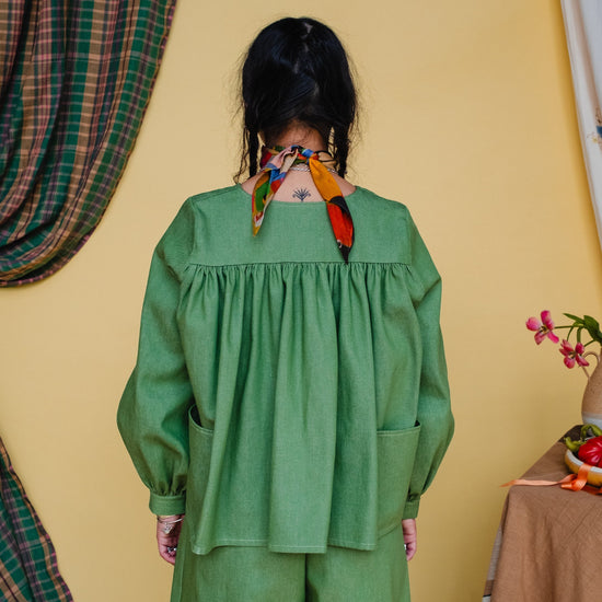 Person wearing a green outfit with colorful accessories in a room setting.