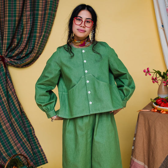Person wearing a green outfit standing in a room with a yellow wall and decorative elements.