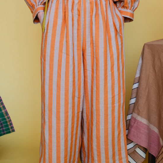 Orange and white striped outfit with a belt on a yellow background