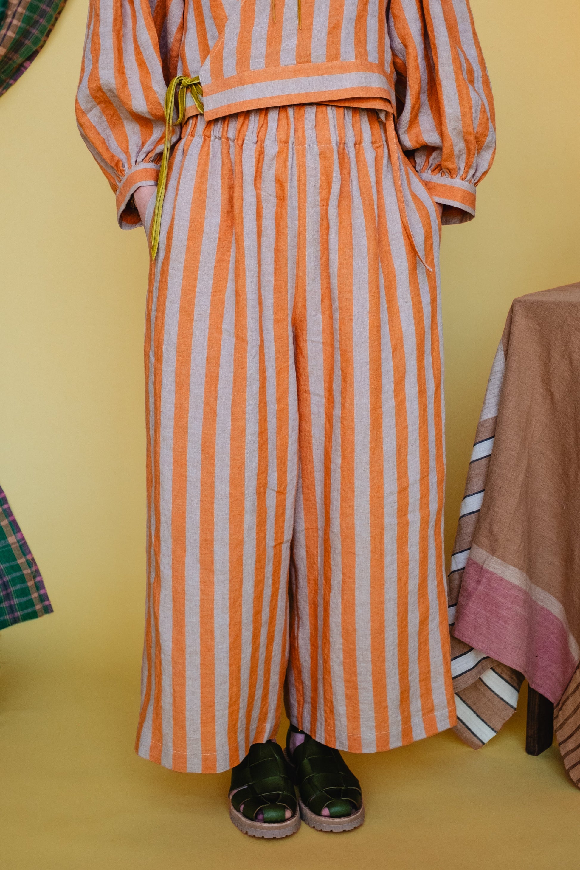 Orange and white striped outfit with a belt on a yellow background