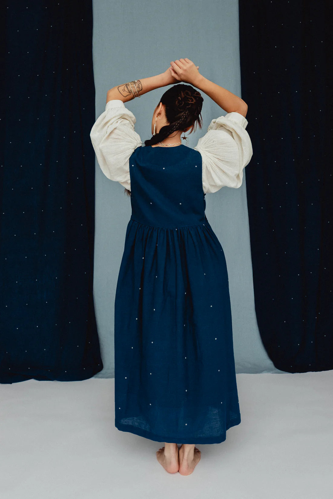 Person wearing a blue dress with white embroidered posies against a blue backdrop