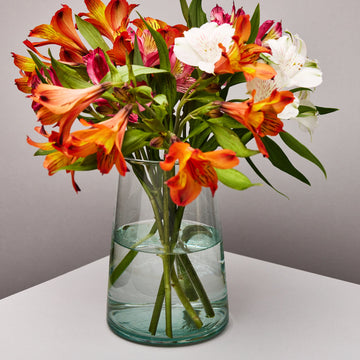 Clear glass vase with colorful flowers on a neutral background