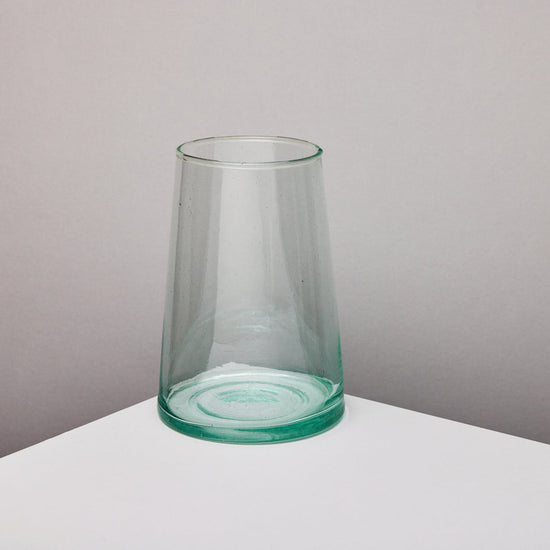 Clear glass vase on a white surface with a taupe background