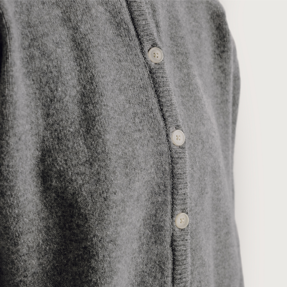 Close-up of a gray cardigan with button details on a light gray background