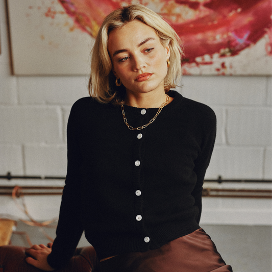 Woman wearing a black cardigan with white buttons in an indoor setting