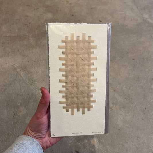 Hand woven paper weave with a geometric pattern, held in a person's hand.