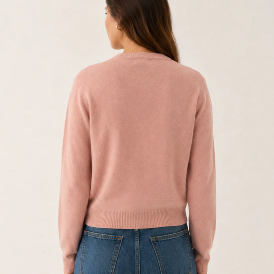 model wearing blush pink knitted cardigan back view paired with blue jeans on a white background
