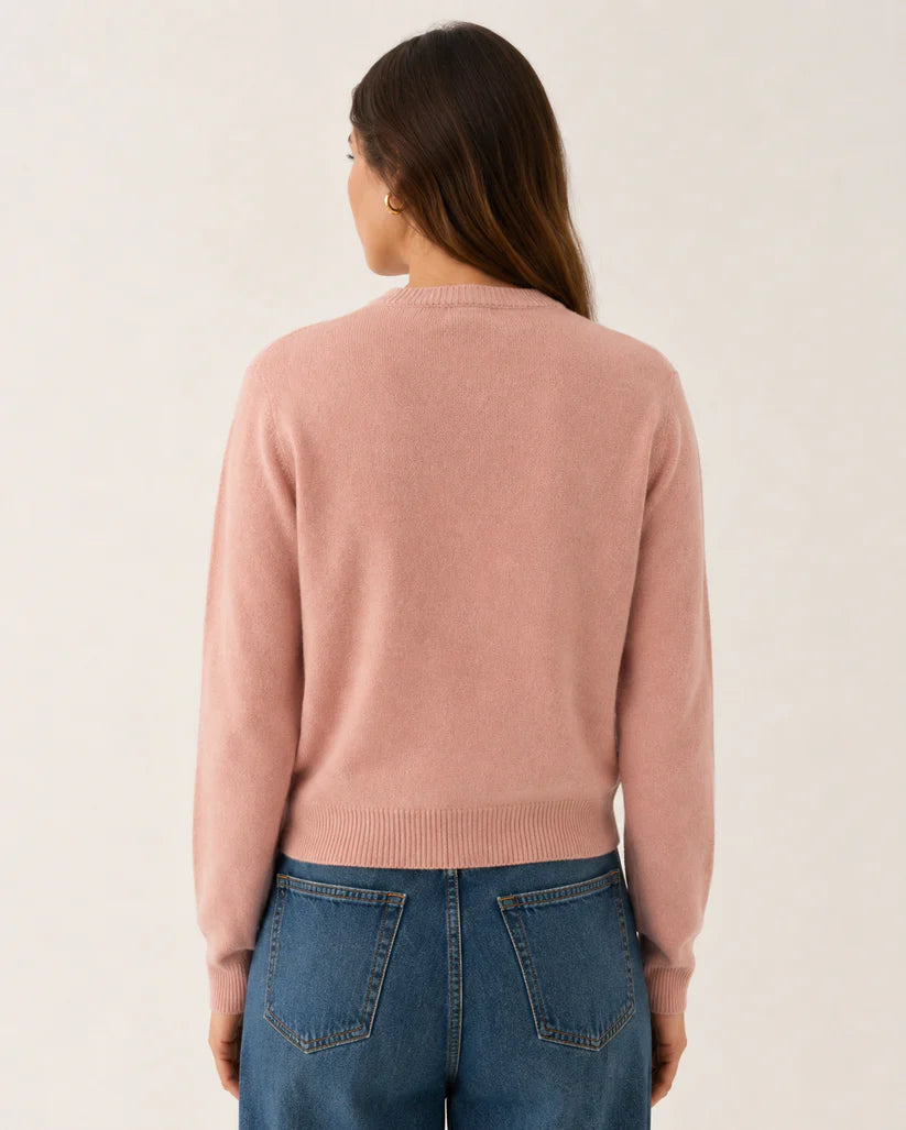 model wearing blush pink knitted cardigan back view paired with blue jeans on a white background