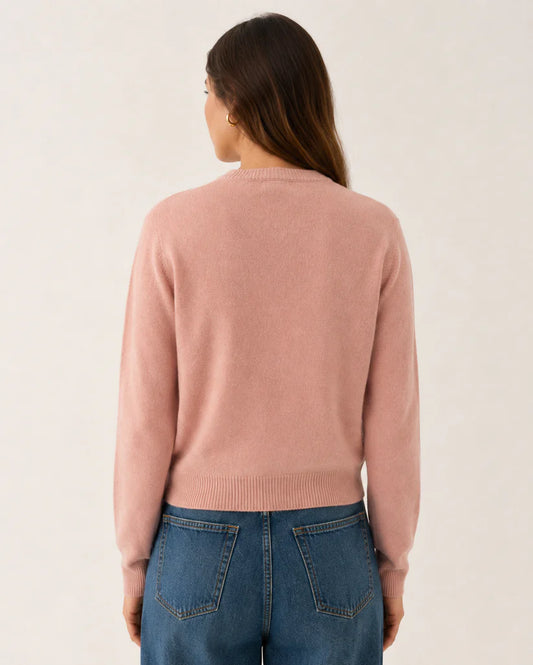 model wearing blush pink knitted cardigan back view paired with blue jeans on a white background