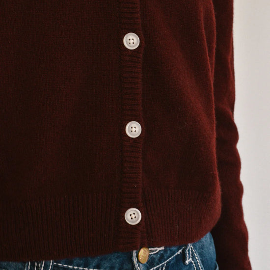 Close-up of a port button-up cardigan worn over blue jeans on a white background