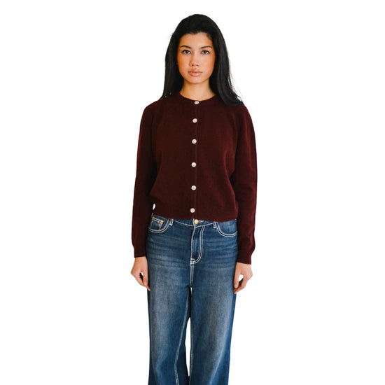 Woman wearing a port cardigan and blue jeans on a white background