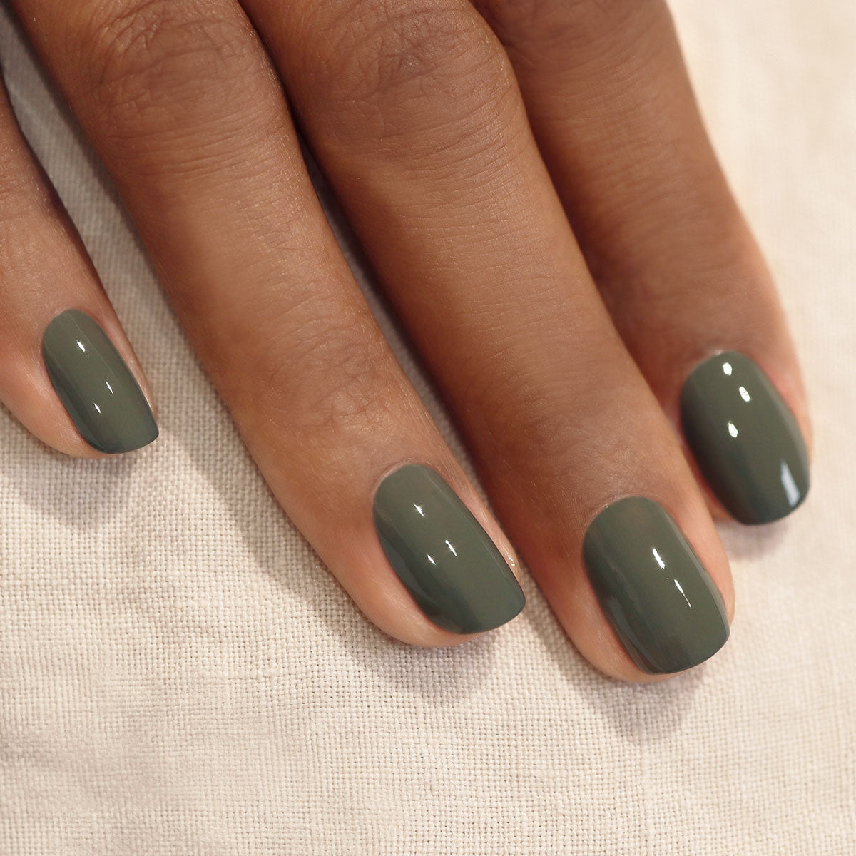 hands with khaki nail varnish on a cream background 