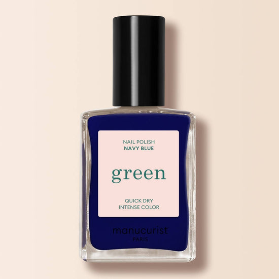 a navy blue nail varnish in a bottle on a cream background 