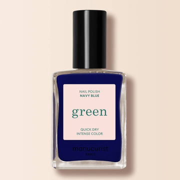 a navy blue nail varnish in a bottle on a cream background 