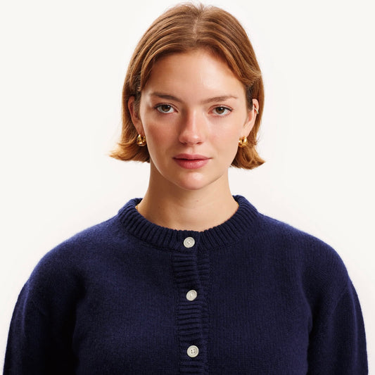 Woman wearing a navy blue cardigan with a plain background