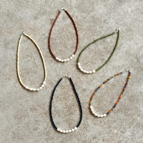 Five beaded necklaces on a beige background 