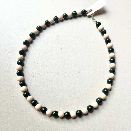 Beaded necklace with green and pink beads on a white background
