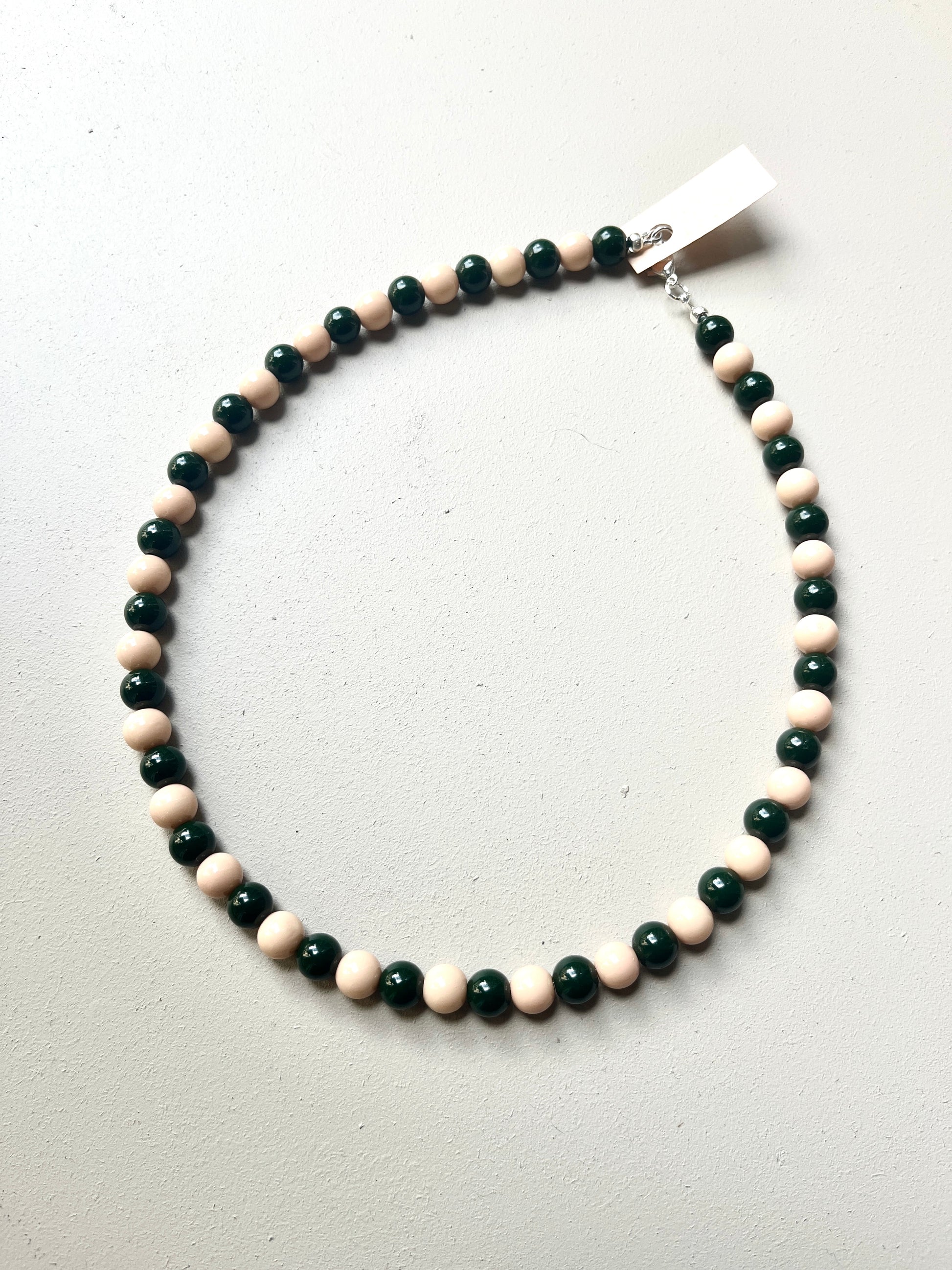 Beaded necklace with green and pink beads on a white background