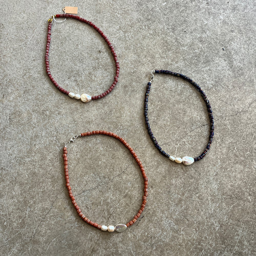 Three beaded necklaces on a textured gray surface