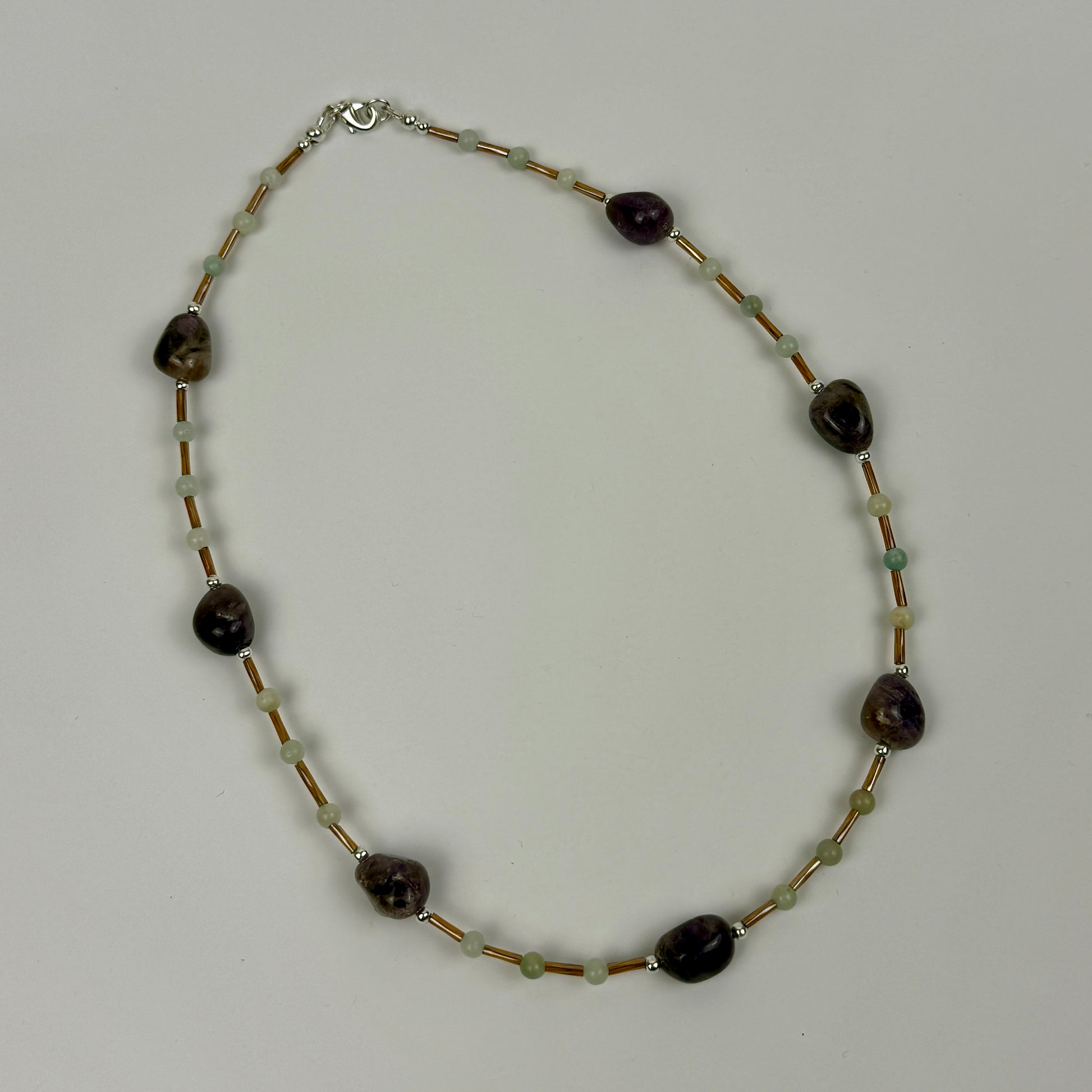 Necklace with dark beads and gold beads on a light grey background