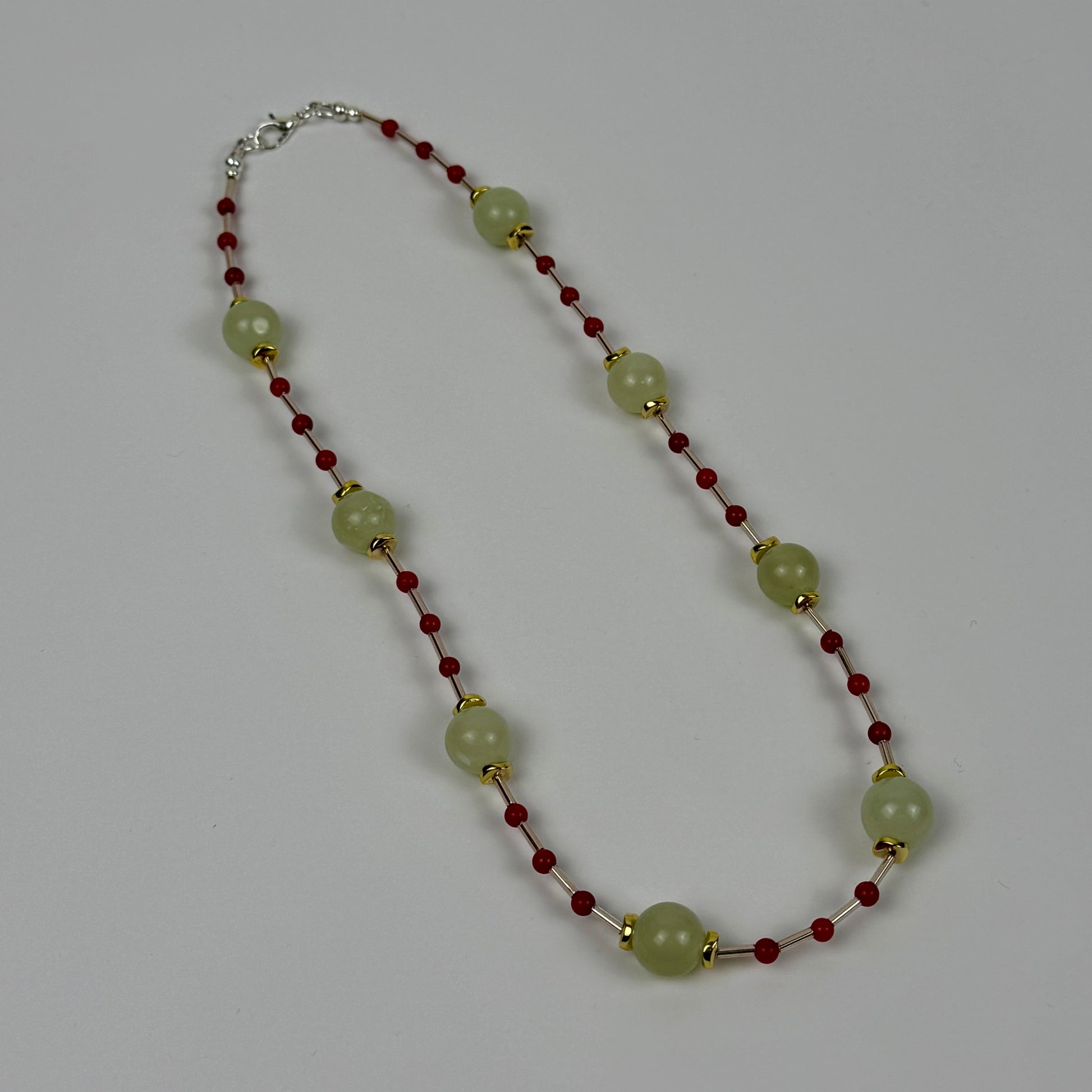 Necklace with green beads and red accents on a grey background