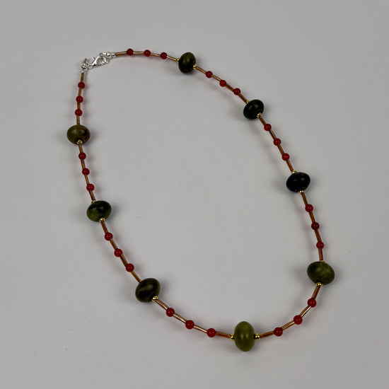 Necklace with green and red beads on a gray background