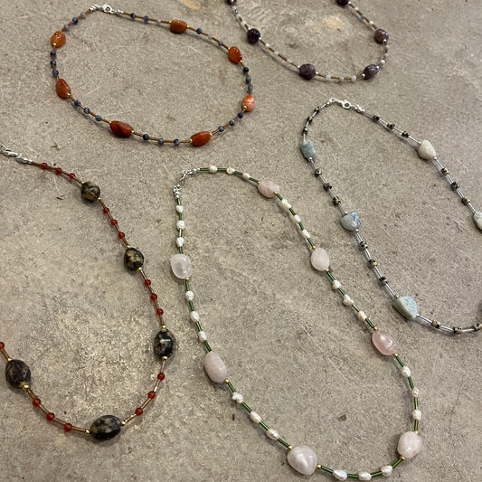 Multiple beaded necklaces on a textured concrete surface