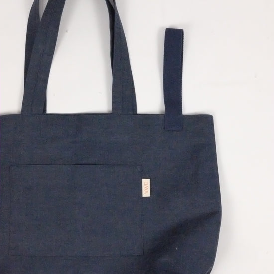 Navy blue tote bag with a pocket on a light gray background