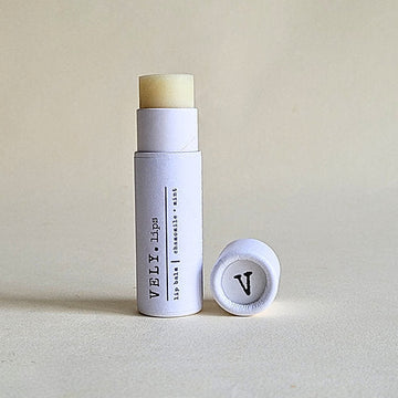 Natural Lip balm with a white container and visible brand logo on a light background