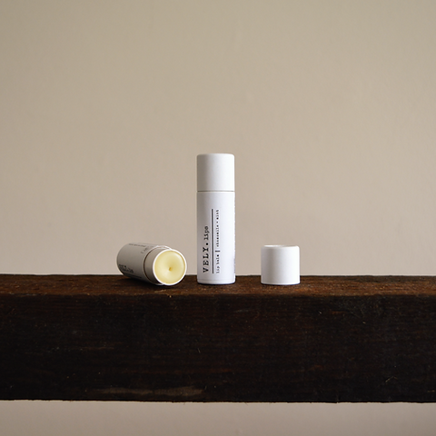 natural white packaged lip balm on a wooden shelf with a neutral background