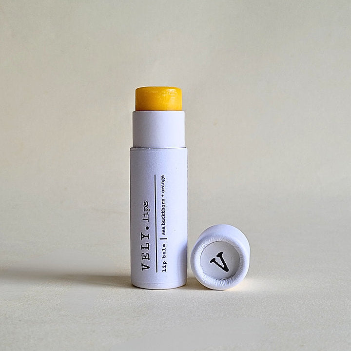 Natural white packaged lip balm stick and visible branding on a light grey background