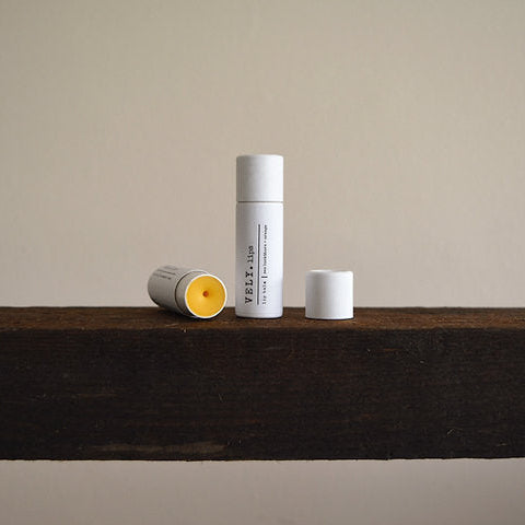 Natural lip balm in white cylindrical containers on a wooden surface with a neutral background