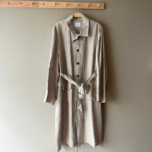 Beige trench coat hanging on a wooden hanger against a plain wall.