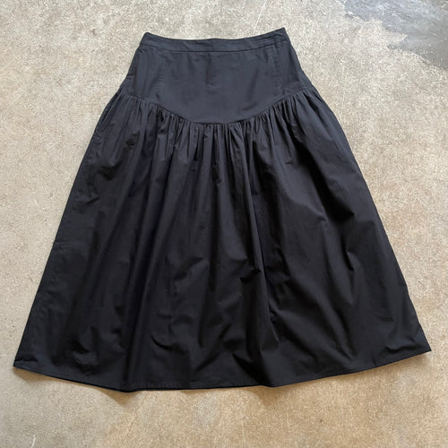 Black skirt on a textured beige surface