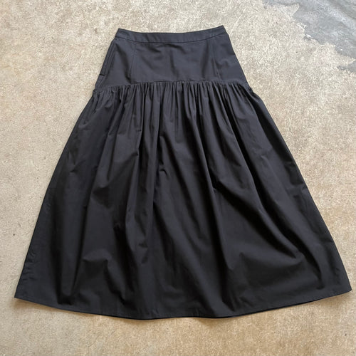 Black high waisted skirt on a textured beige surface