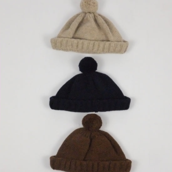 Three knit hats in beige, black, and brown on a white background