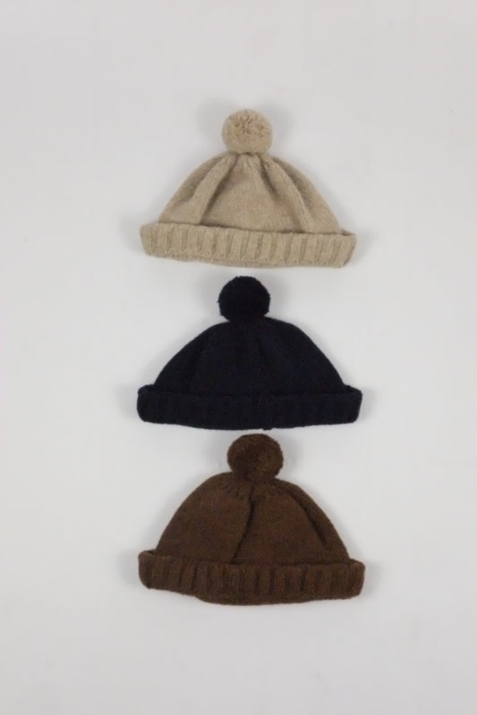 Three knit hats in beige, black, and brown on a white background