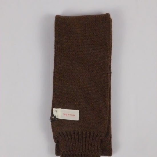 Brown knitted scarf with a label on a light gray background