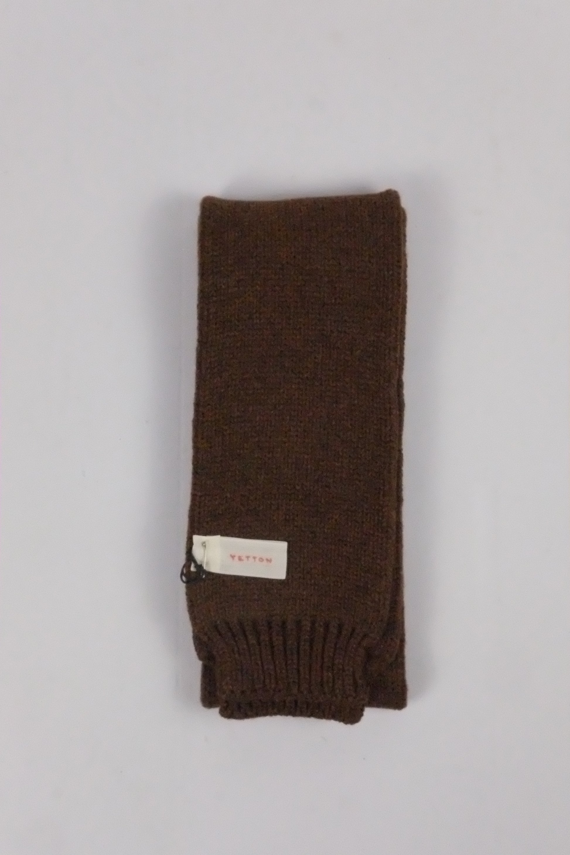 Brown knitted scarf with a label on a light gray background